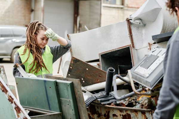 Tired volunteer sorting metail pieces at scrapyard