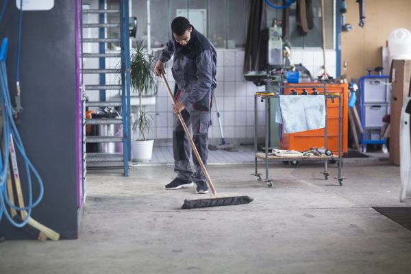 Worker sweeping the floor in a tidy workshop.